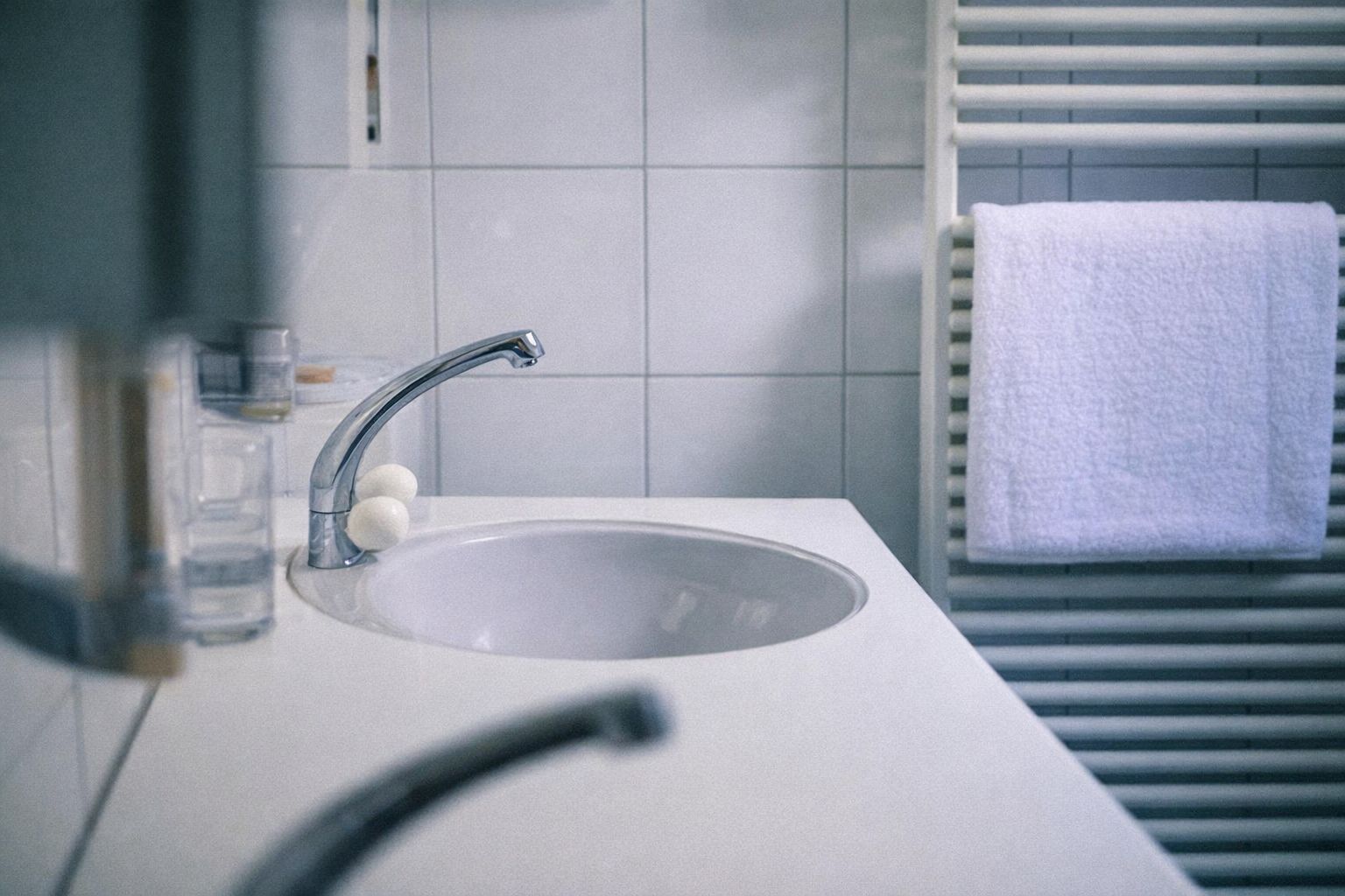 Vitt handfat med blandare och handdukstork i ett badrum.