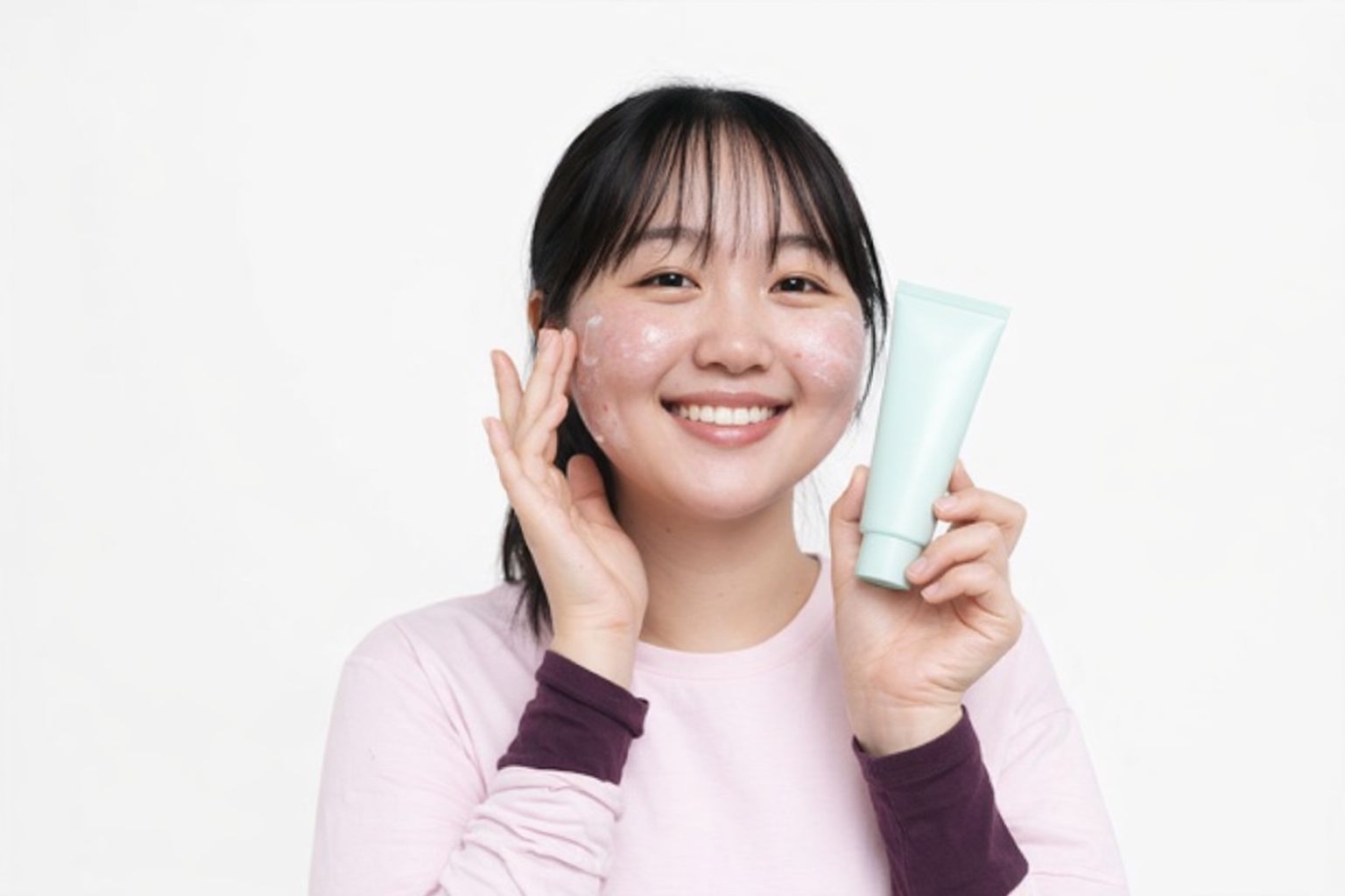 Leende kvinna applicerar lugnande ansiktskräm mot rodnad.