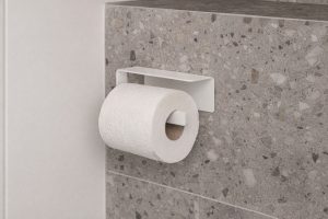 Vit modern toalettpappershållare monterad på en stenvägg.