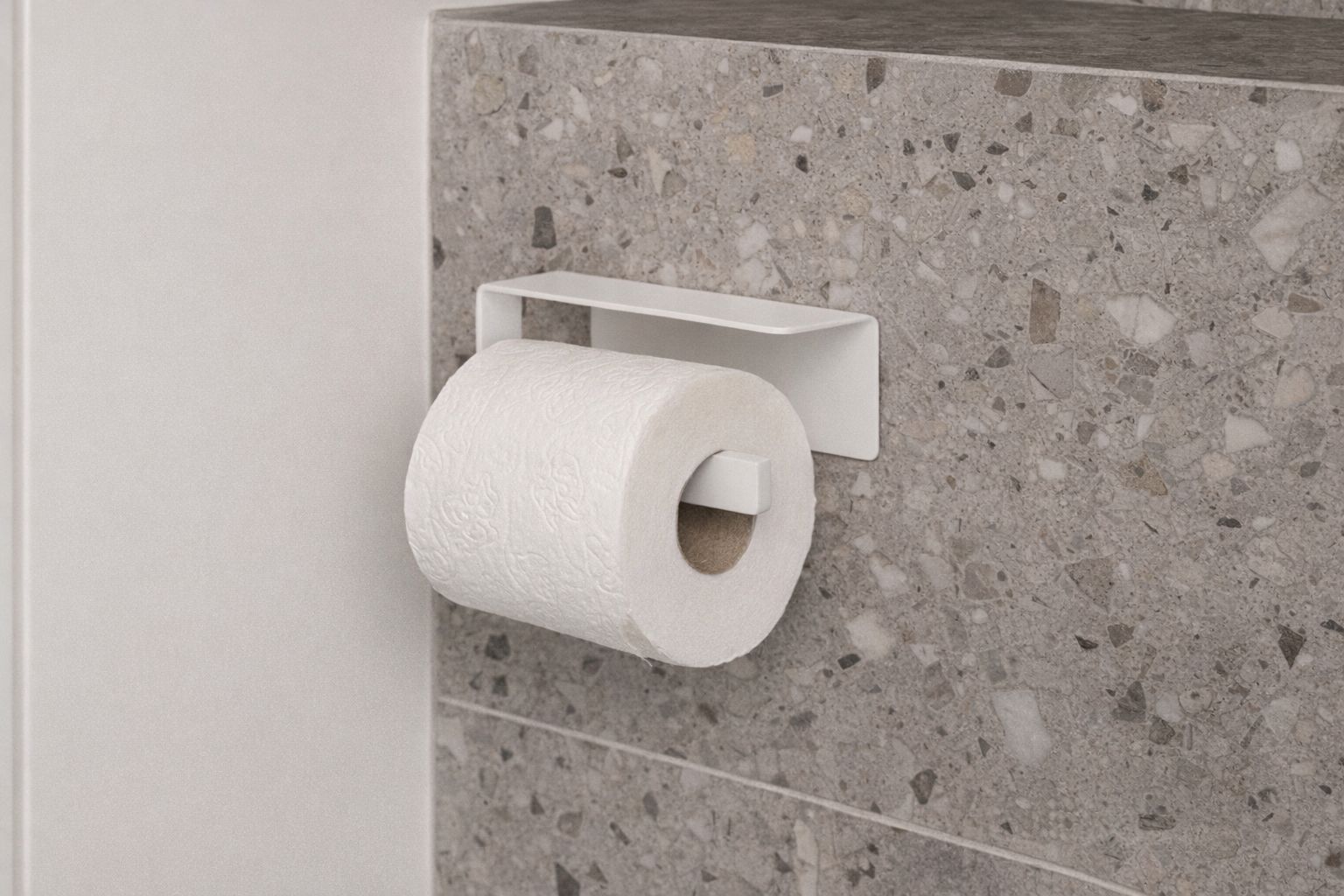 Vit modern toalettpappershållare monterad på en stenvägg.